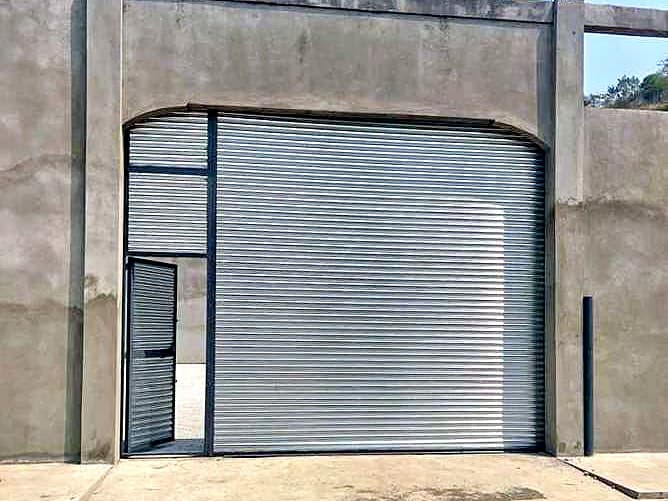 Portón enrollable con puerta peatonal en bodega